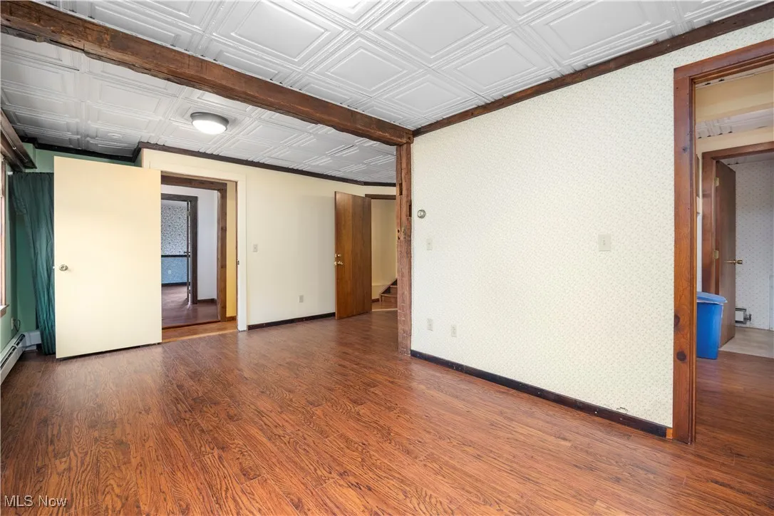 Empty room with dark wood finished floors and an ornate ceiling