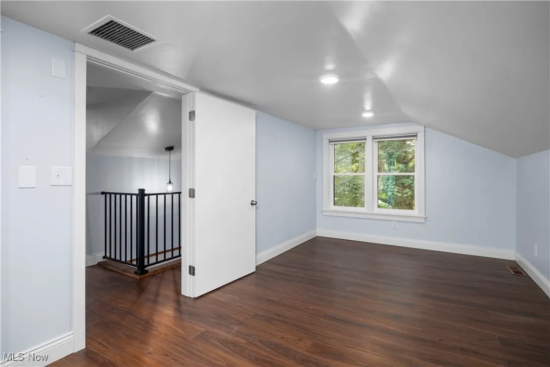 Additional living space with dark wood finished floors and vaulted ceiling