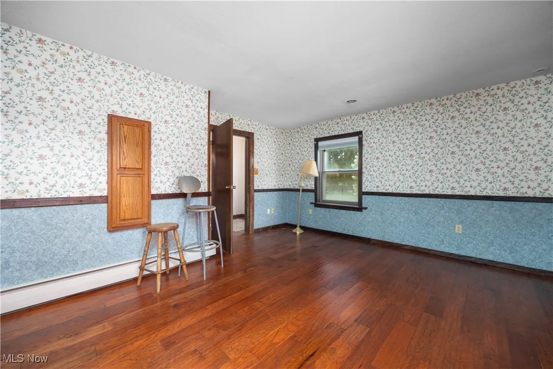 Empty room featuring a baseboard radiator and dark wood-style floors