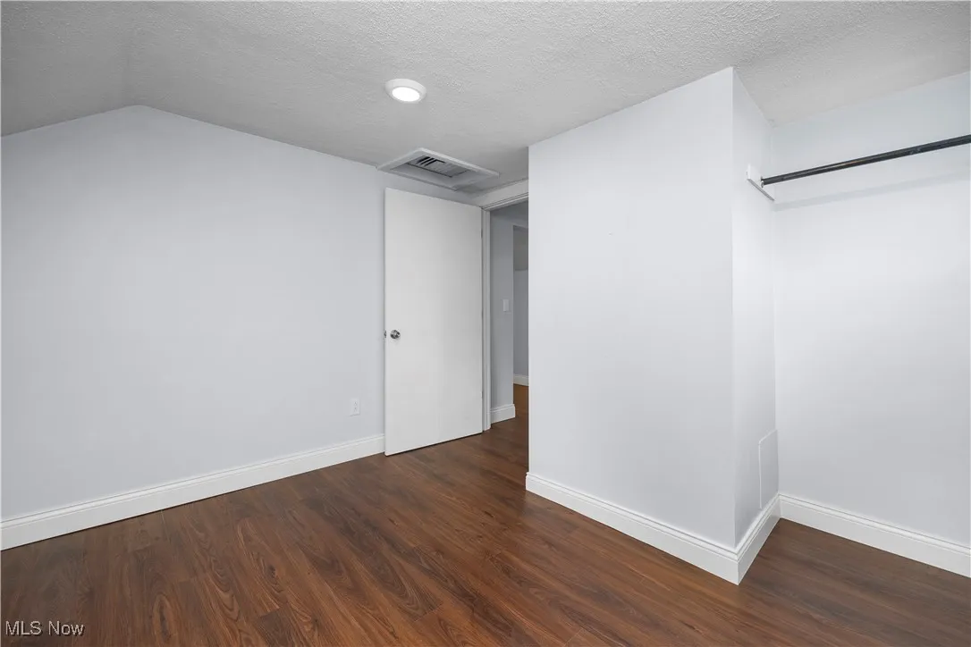 Unfurnished bedroom with a textured ceiling, dark wood finished floors, and a closet