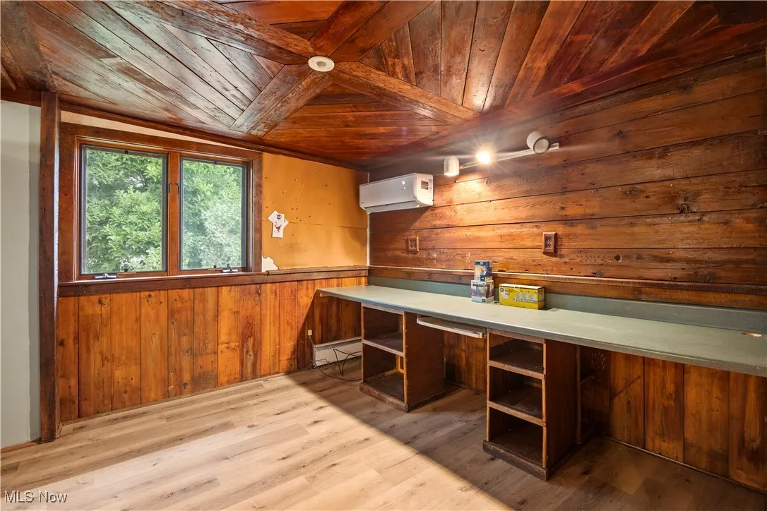 Bar area featuring wooden walls, wooden ceiling, light wood finished floors, light countertops, and a wall unit AC