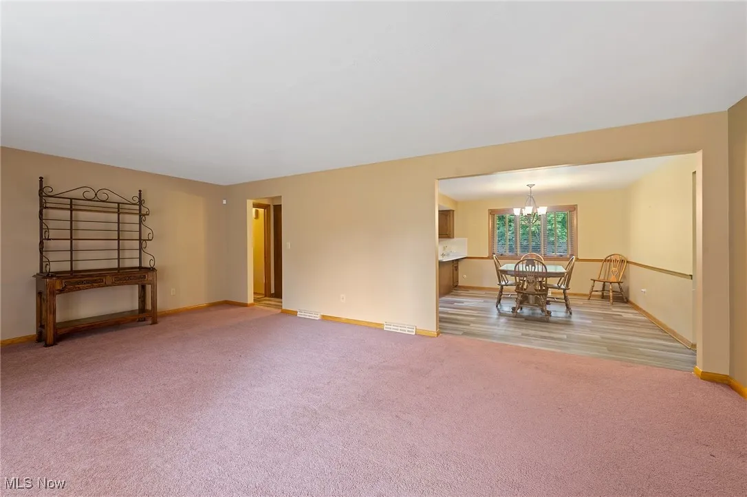 Spare room featuring light carpet and a chandelier