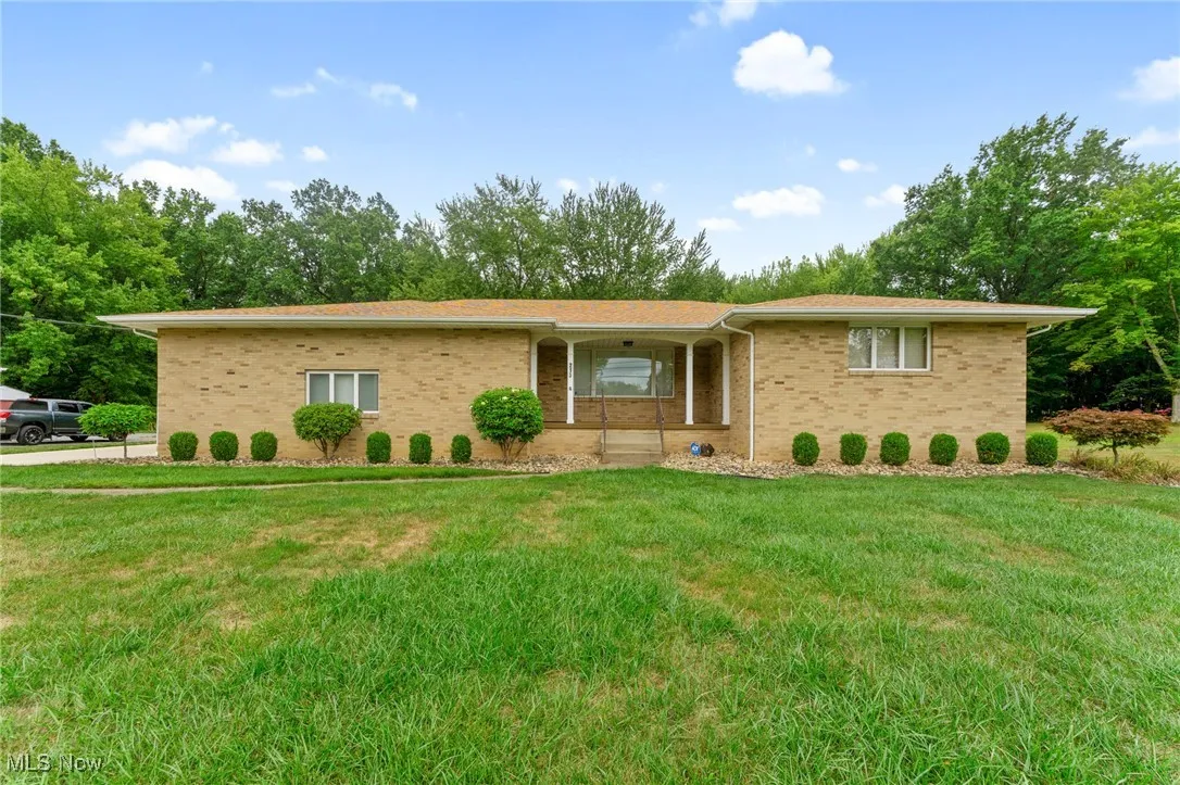 View of front of property with brick siding, a front yard, and covered porch