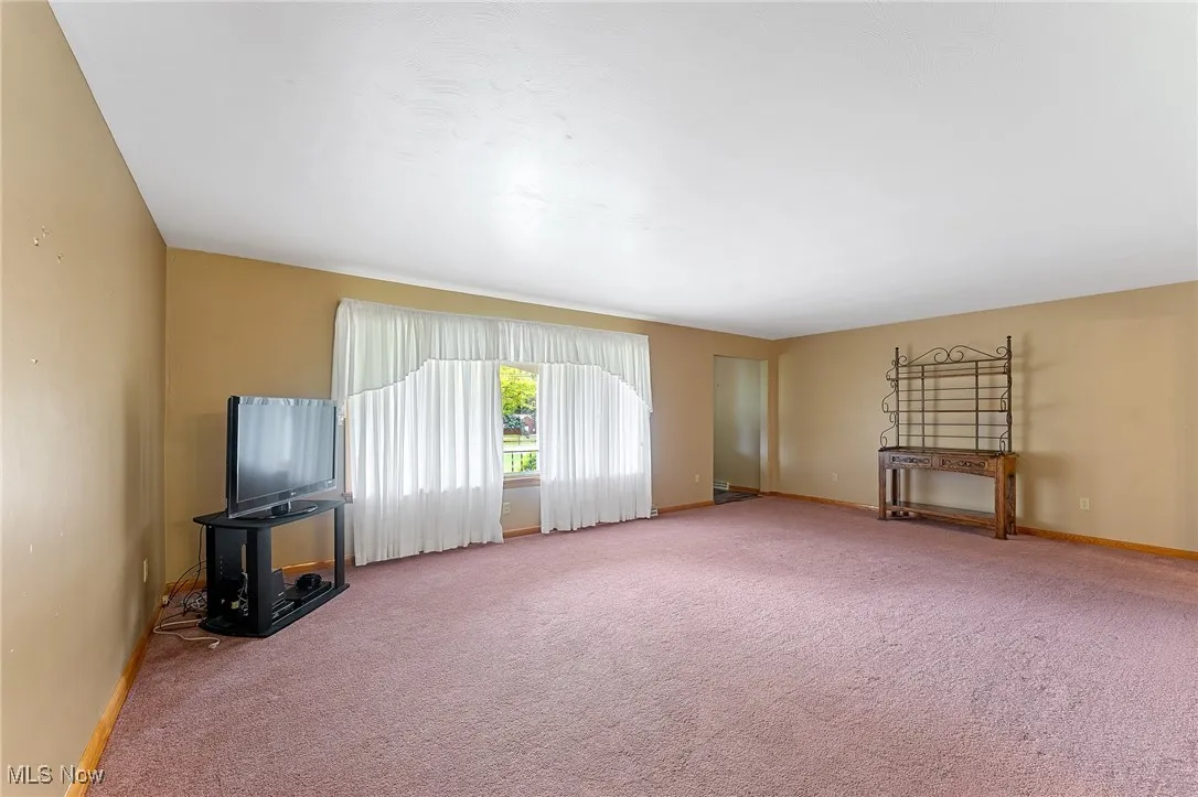 Unfurnished living room featuring carpet floors and baseboards