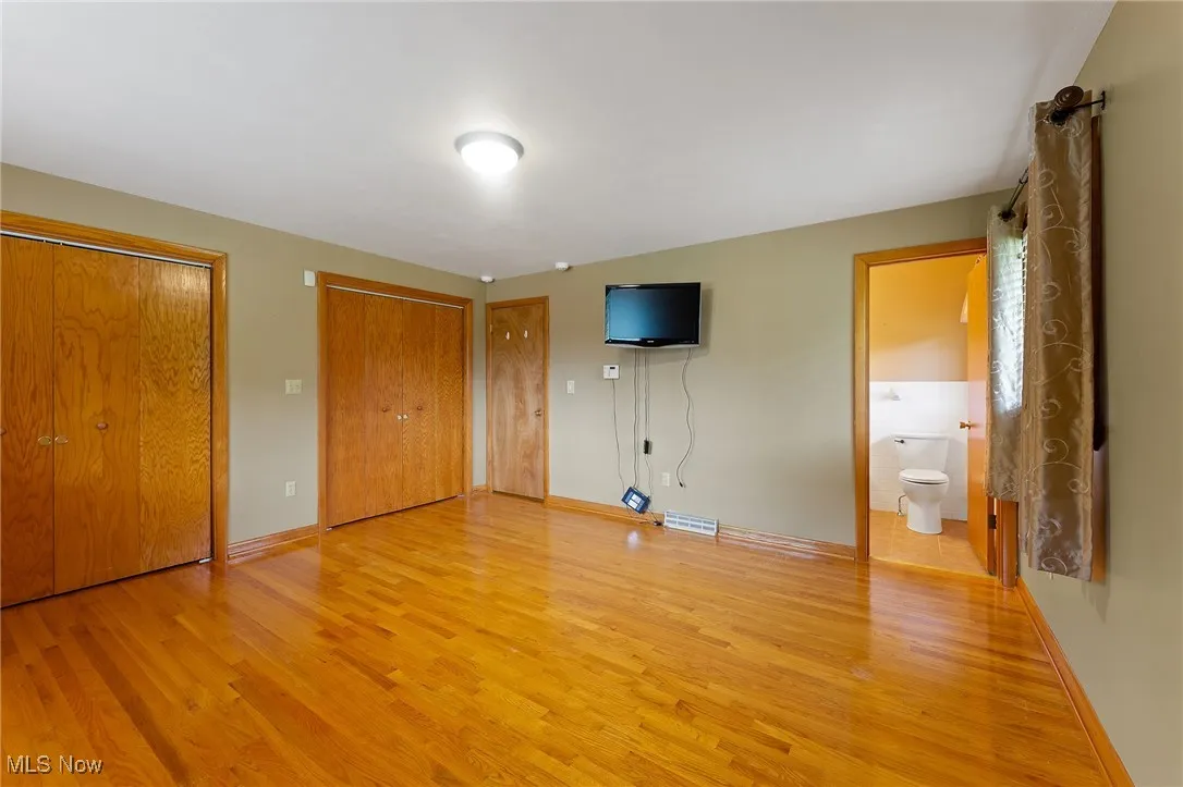 Master bedroom with light wood-type flooring and two closets