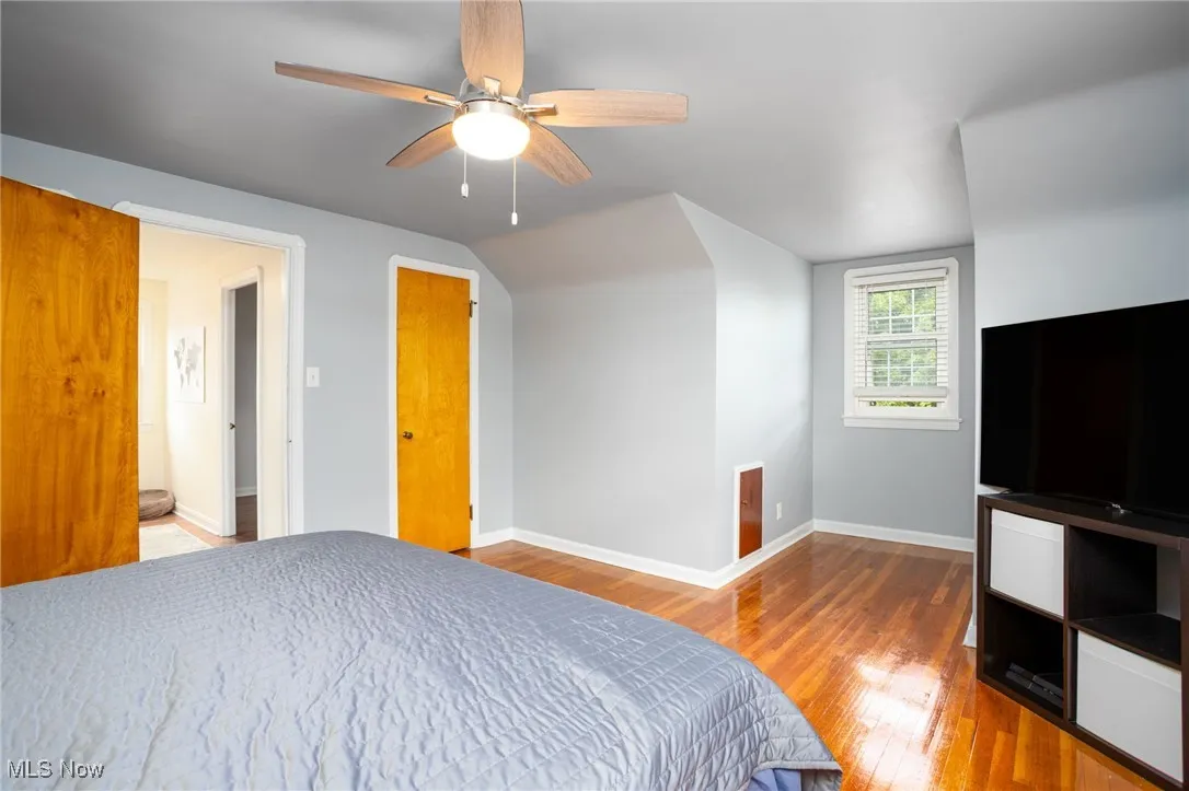 Bedroom with hardwood flooring, a ceiling fan, and vaulted ceiling