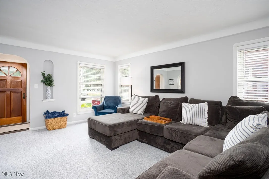 Carpeted living room with healthy amount of natural light and arched walkways