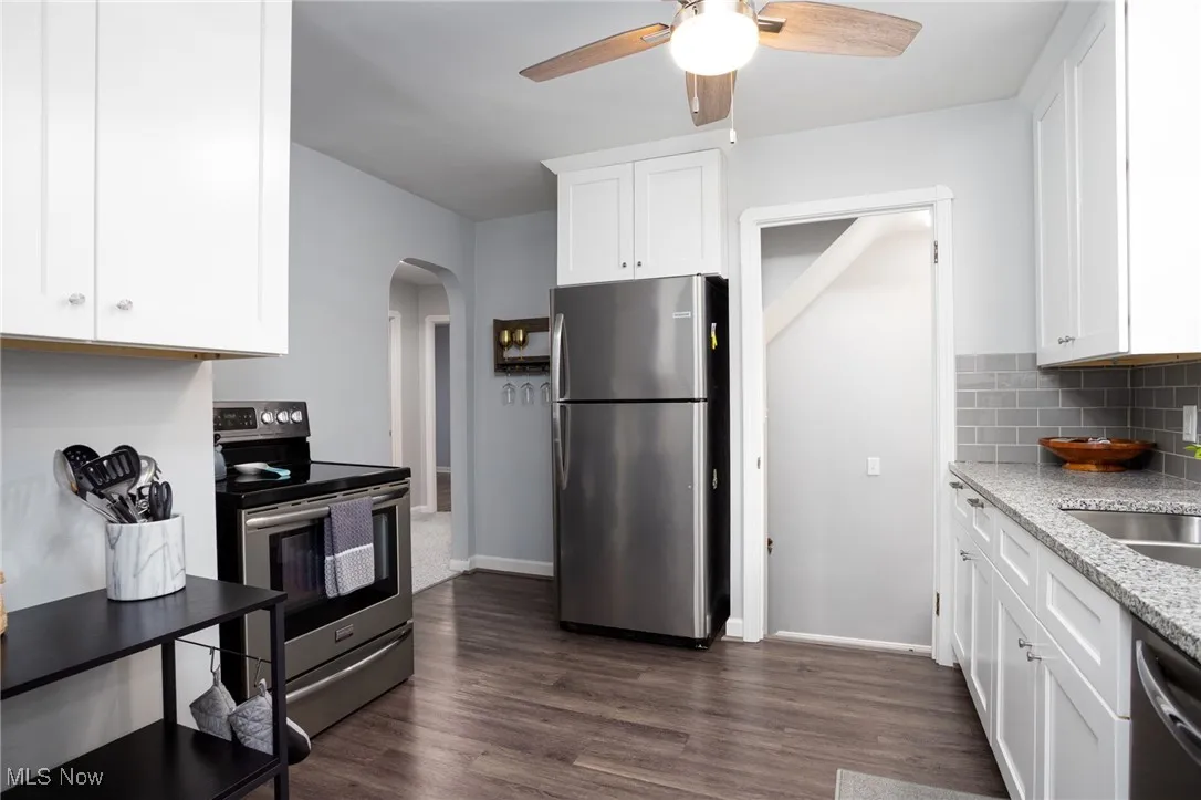 Kitchen with appliances with stainless steel finishes, white cabinets, and vinyl flooring