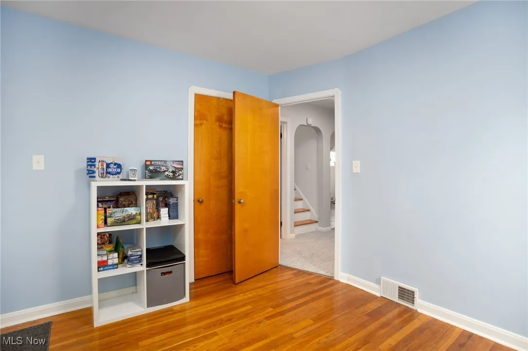 Unfurnished bedroom featuring arched walkways, hardwood floors, and a closet