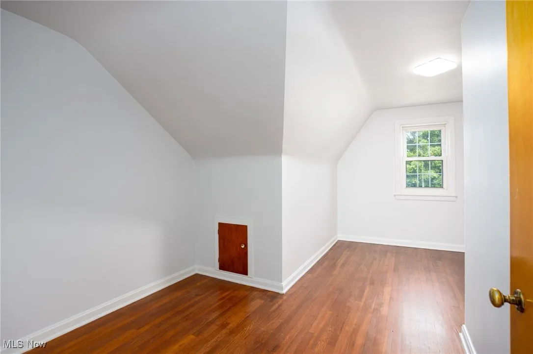 Bonus room with hardwood flooring and vaulted ceiling