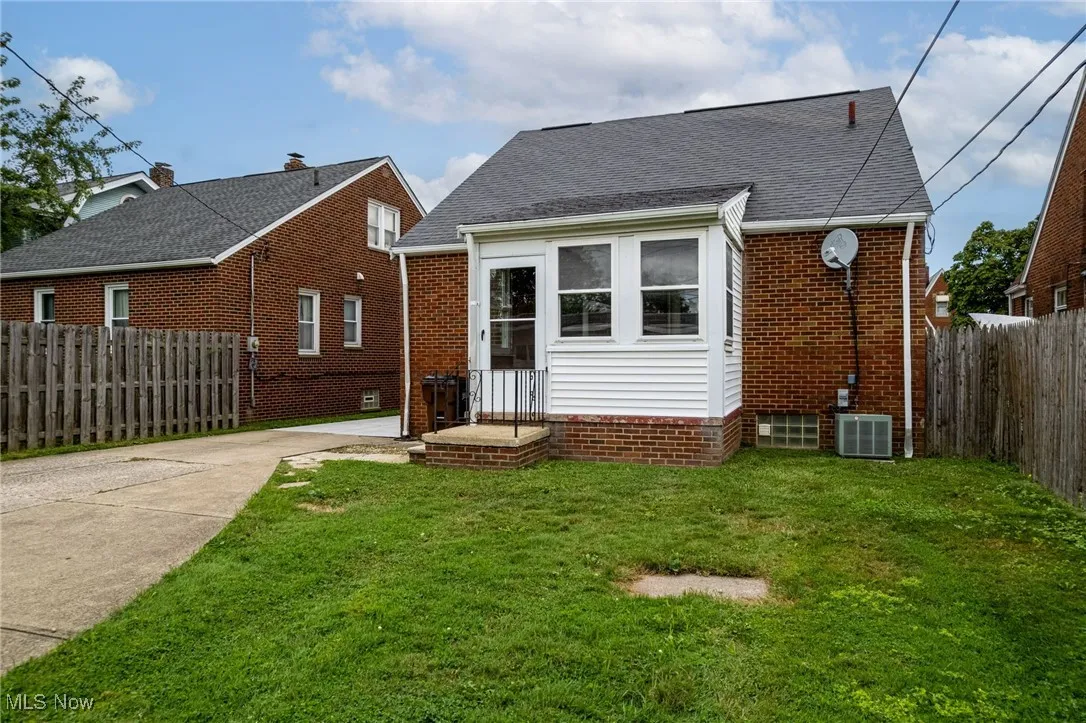Rear view of property featuring driveway, brick siding, and a shingled roof