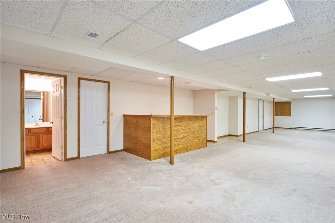 Finished lower level with wet bar, drop ceiling, and light colored carpet