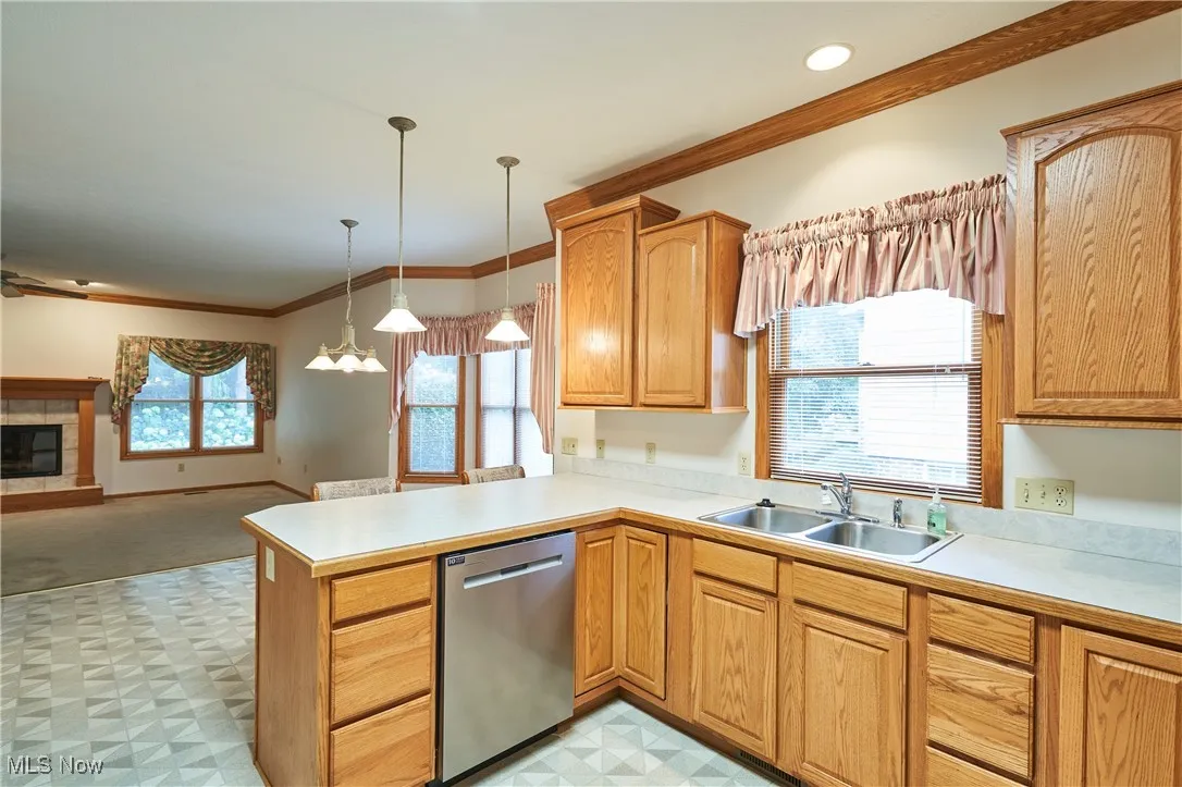 Kitchen featuring crown molding, oak cabinets, peninsula with pennant lights, bar area and  eating area