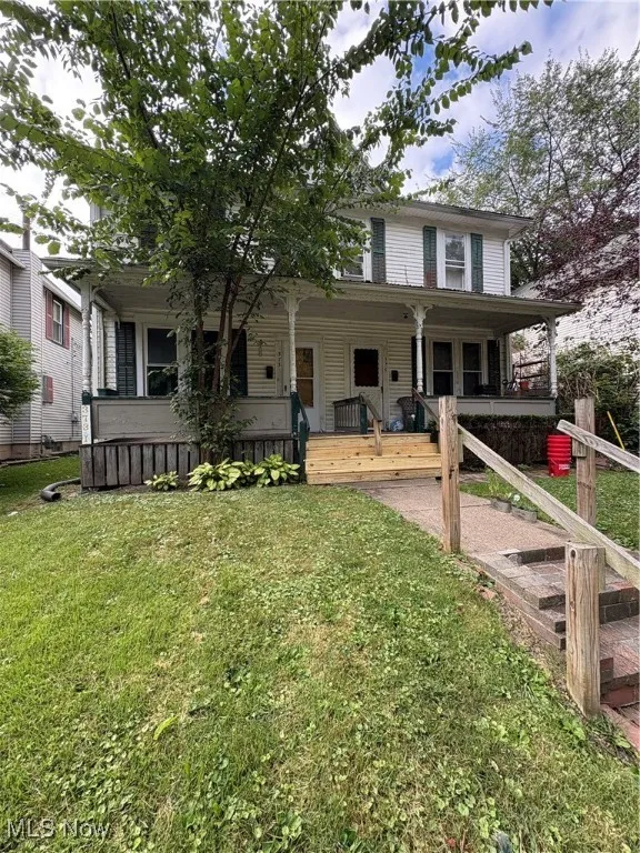 View of front facade featuring covered porch and a front yard