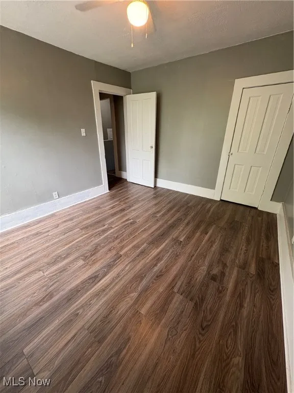 Unfurnished bedroom with dark wood-style floors, a textured ceiling, and a ceiling fan