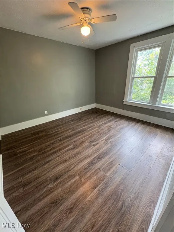 Spare room featuring dark wood finished floors, a textured ceiling, and ceiling fan