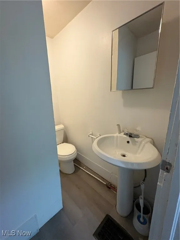 Bathroom with dark wood-type flooring and toilet