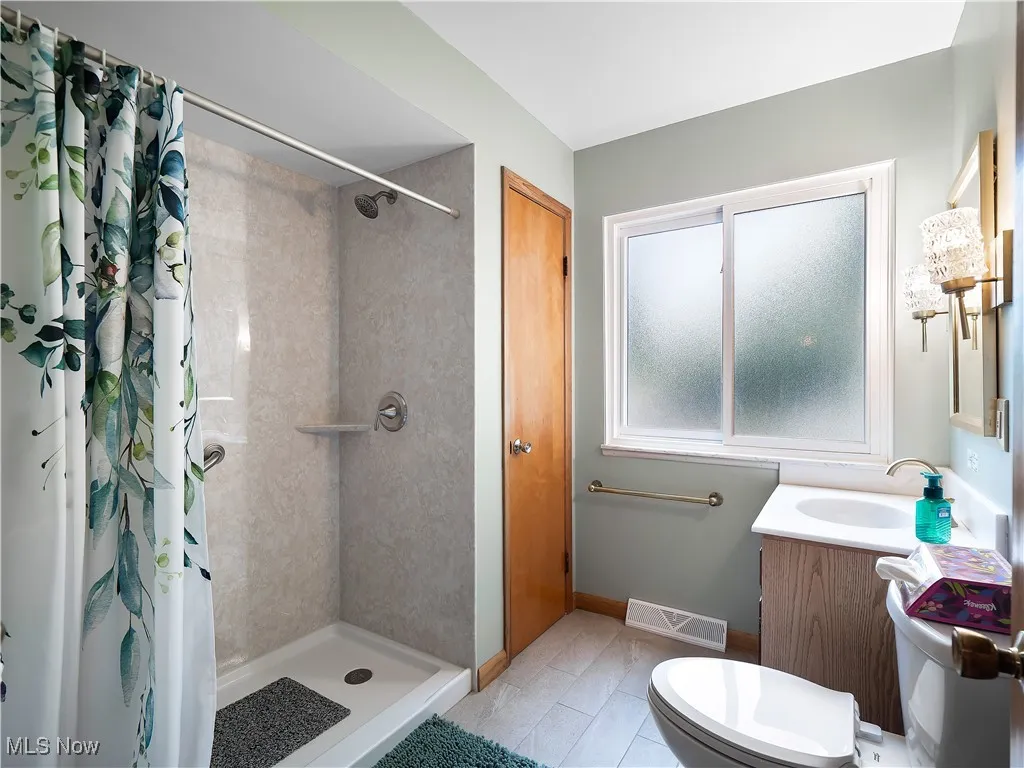 Full bath featuring vanity, a shower stall, and light tile patterned flooring