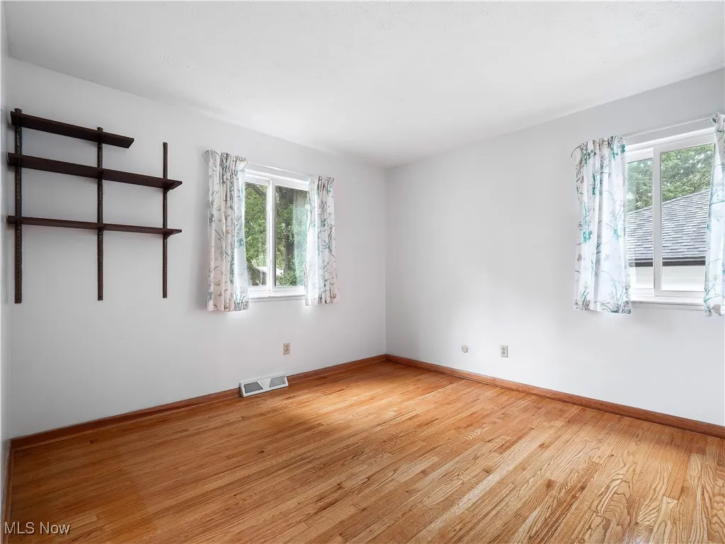 Empty room with light wood-style flooring and healthy amount of natural light
