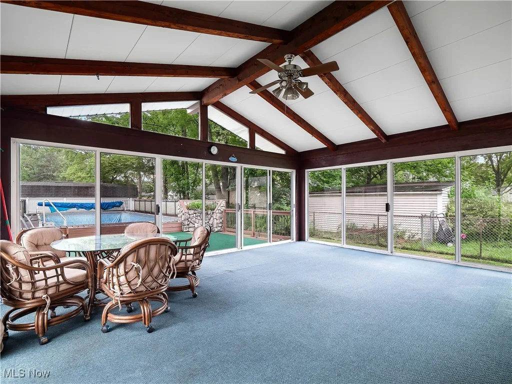 Sunroom / solarium featuring plenty of natural light, carpet, beam ceiling, and high vaulted ceiling