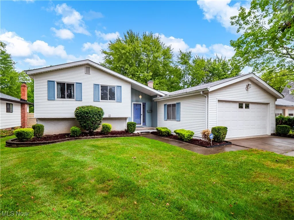 Split level home with an attached garage, driveway, and a front yard