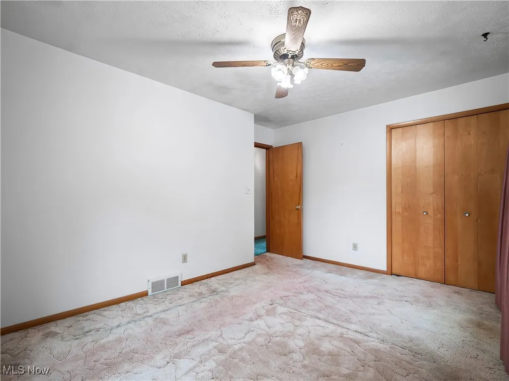 Unfurnished bedroom with a textured ceiling, ceiling fan, a closet, and carpet floors