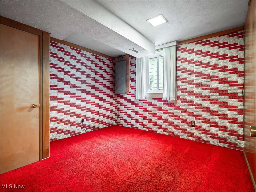 Carpeted empty room with a textured ceiling and electric panel
