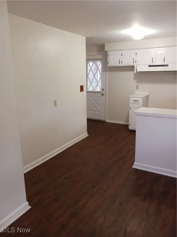 Kitchen featuring white cabinets, light countertops, dark wood finished floors, and exhaust hood