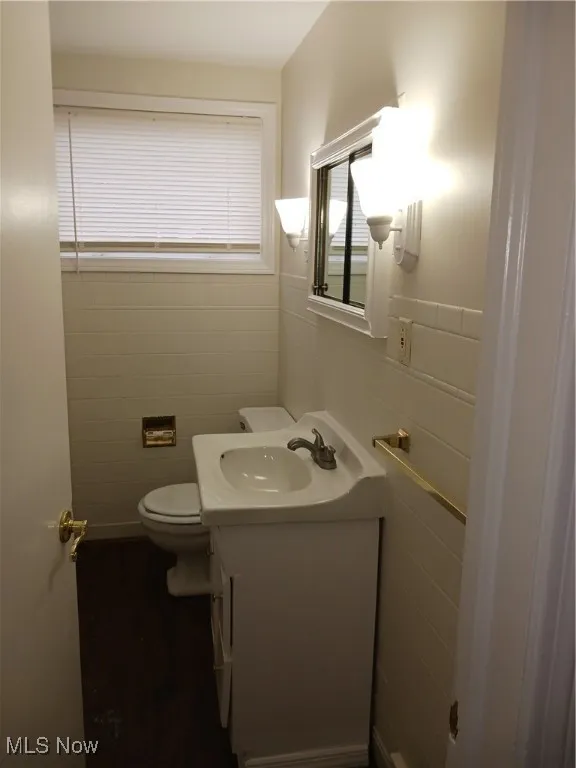 Bathroom featuring tile walls, vanity, and dark wood-style floors