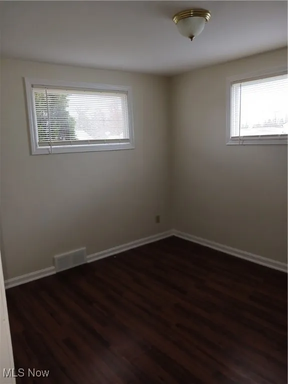 Unfurnished room with dark wood finished floors and baseboards