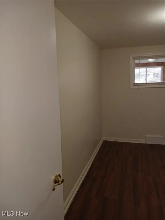 Unfurnished room with dark wood-style floors and baseboards