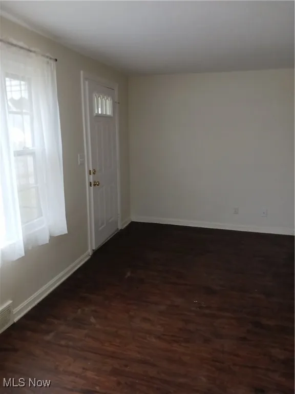 Foyer with dark wood-style floors and baseboards