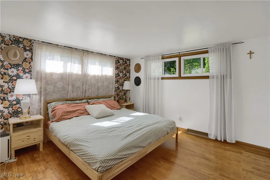 Bedroom with multiple windows, wallpapered walls, and light wood-type flooring