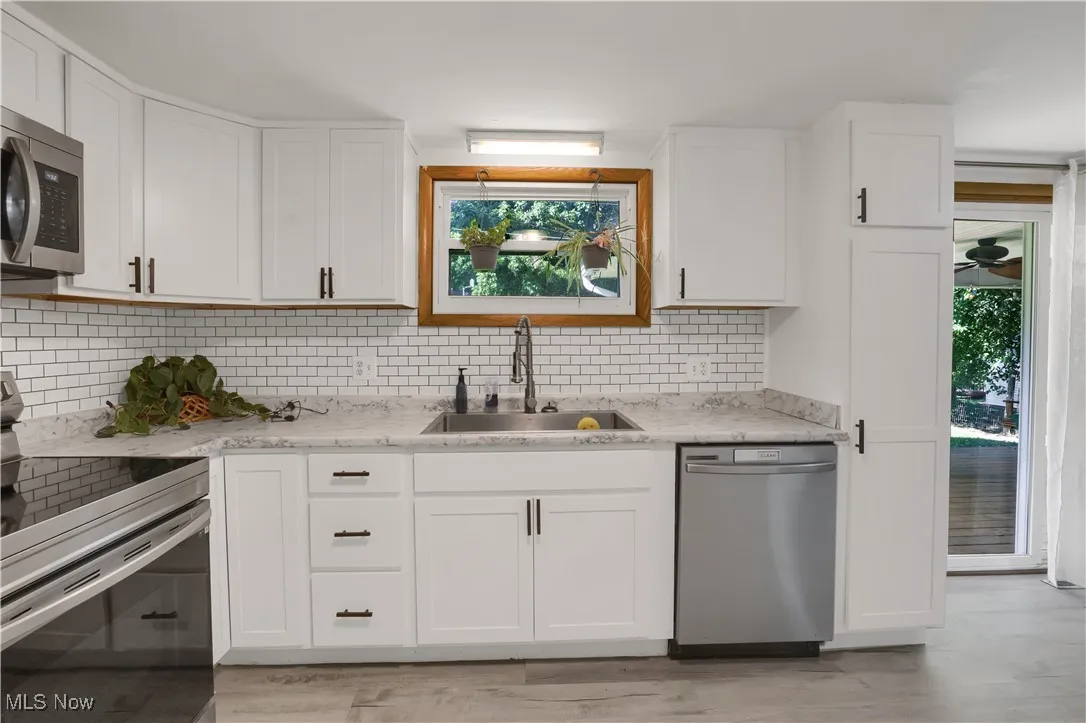 Kitchen with appliances with stainless steel finishes, white cabinetry, healthy amount of natural light, and tasteful backsplash