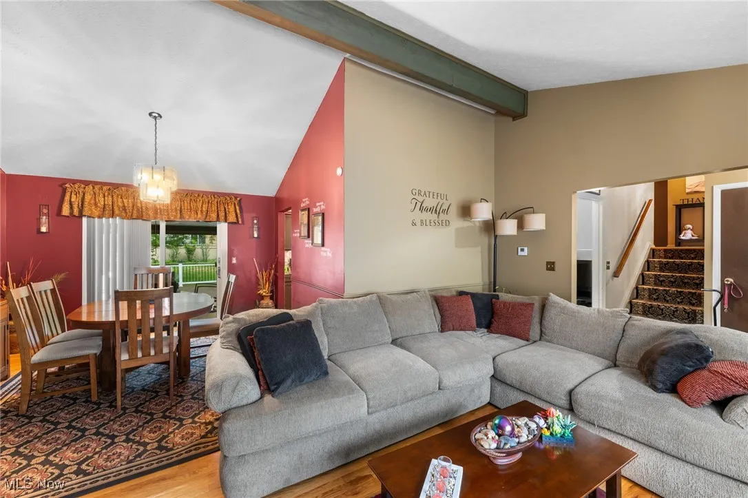 Living room featuring wood finished floors, a chandelier, and stairs