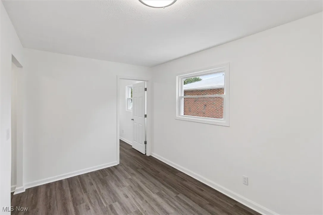 Empty room with dark wood-style floors and baseboards