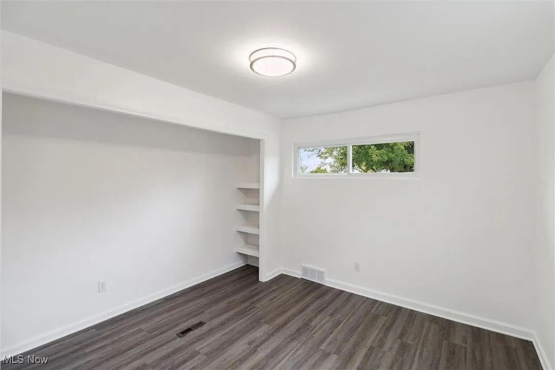 Unfurnished bedroom with dark wood-style flooring and a closet