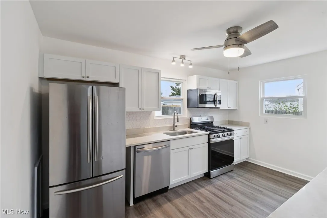 Kitchen with appliances with stainless steel finishes, white cabinetry, light wood-style flooring, and plenty of natural light