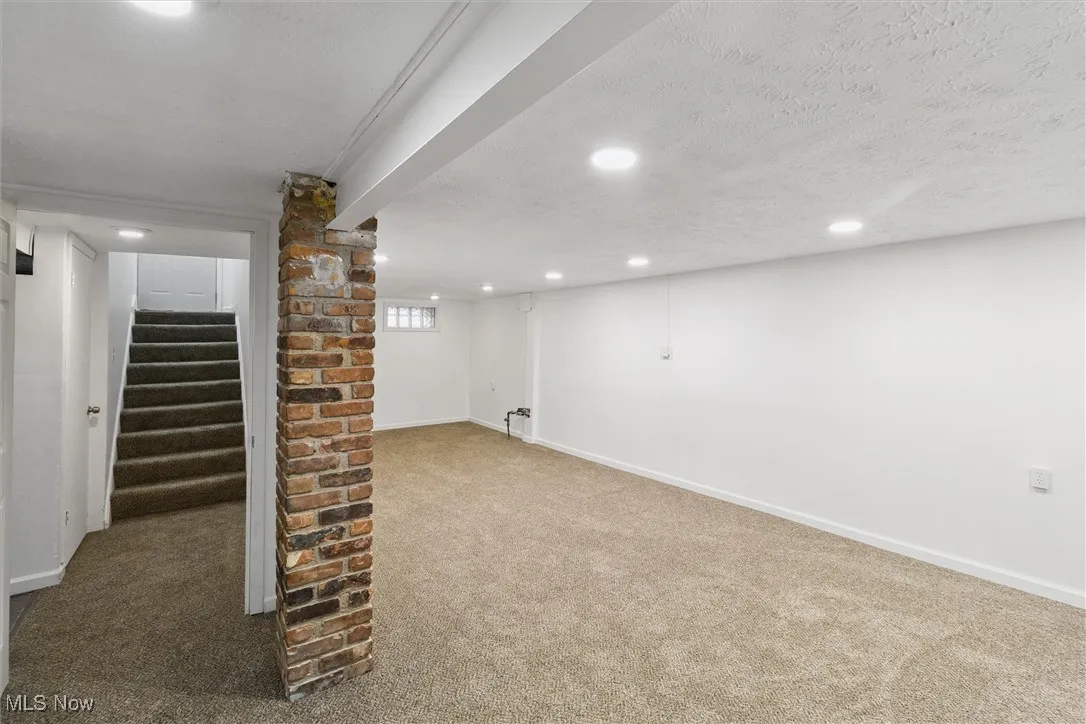 Below grade area with carpet flooring, stairs, recessed lighting, and a textured ceiling