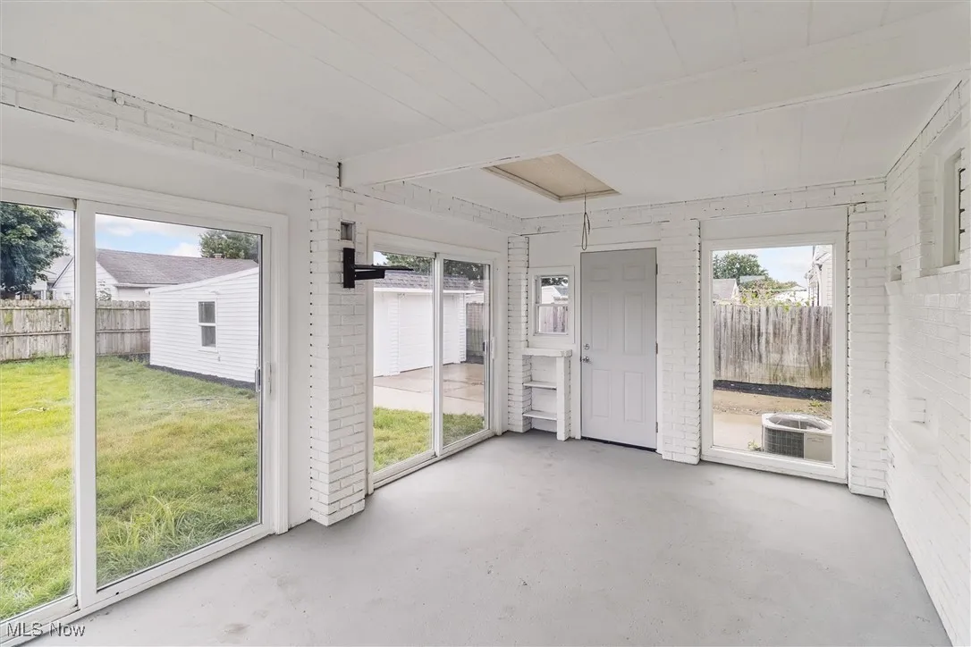 Unfurnished sunroom featuring beam ceiling