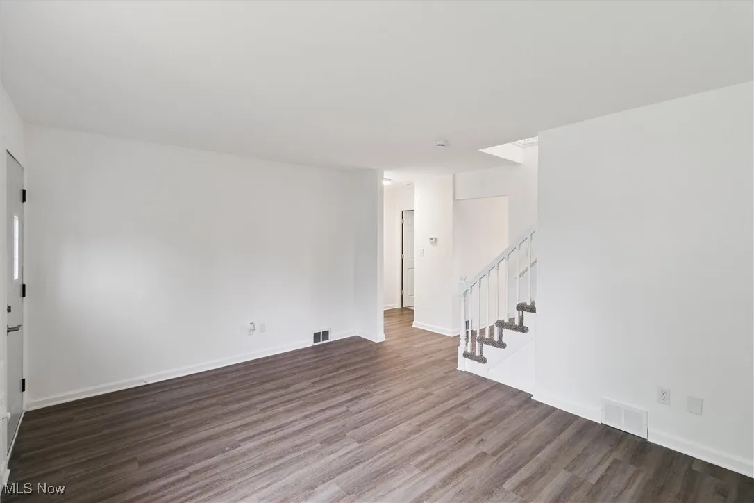 Unfurnished living room featuring stairs and wood finished floors