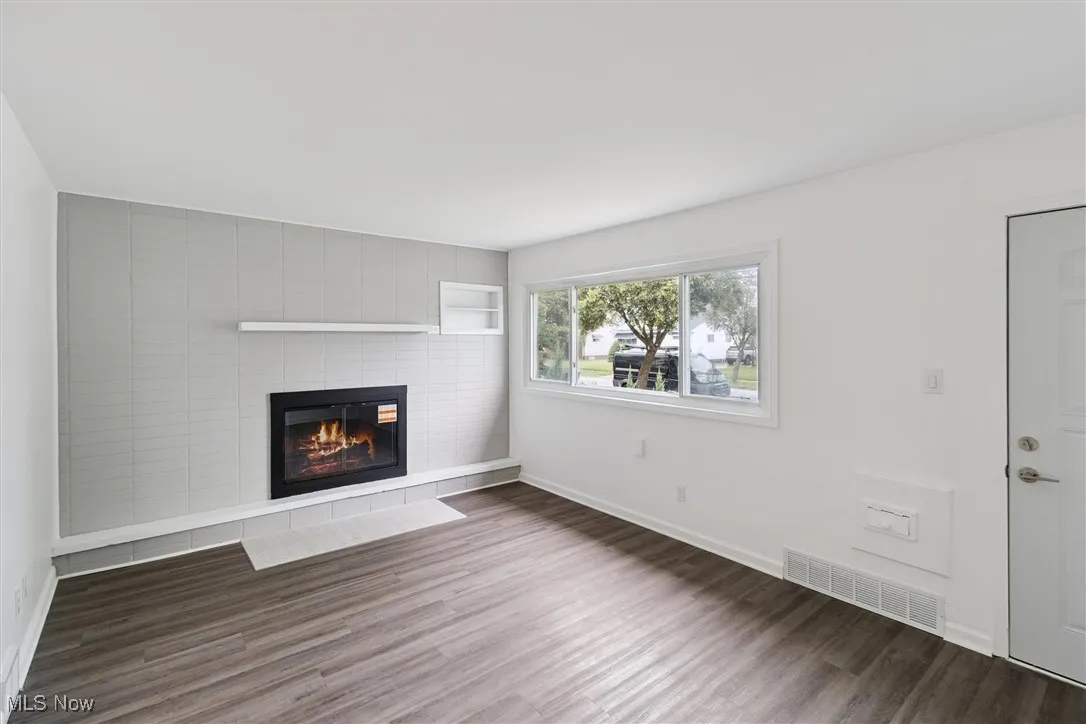 Unfurnished living room featuring wood finished floors and a tile fireplace