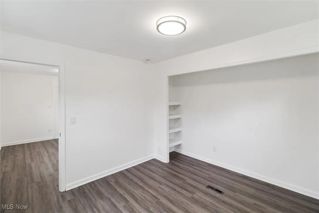 Unfurnished bedroom with dark wood-style floors and a closet