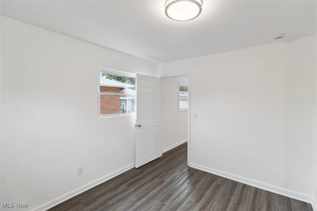 Empty room with dark wood-type flooring and baseboards