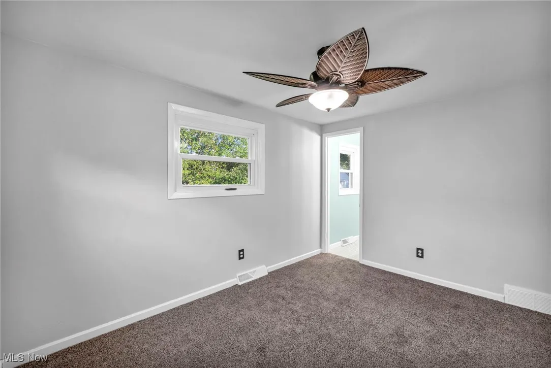 Empty room with carpet floors and ceiling fan