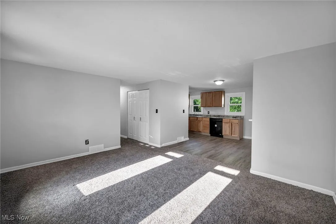 Unfurnished living room with baseboards and dark colored carpet