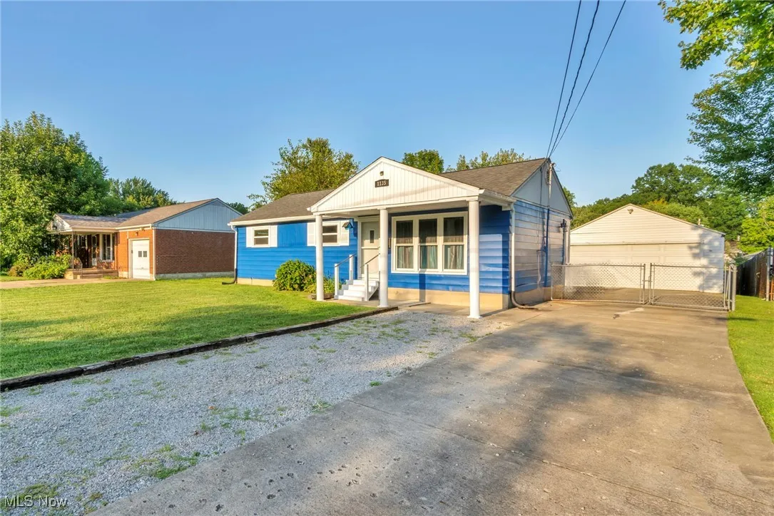 Bungalow featuring an outbuilding, a garage, and a front lawn