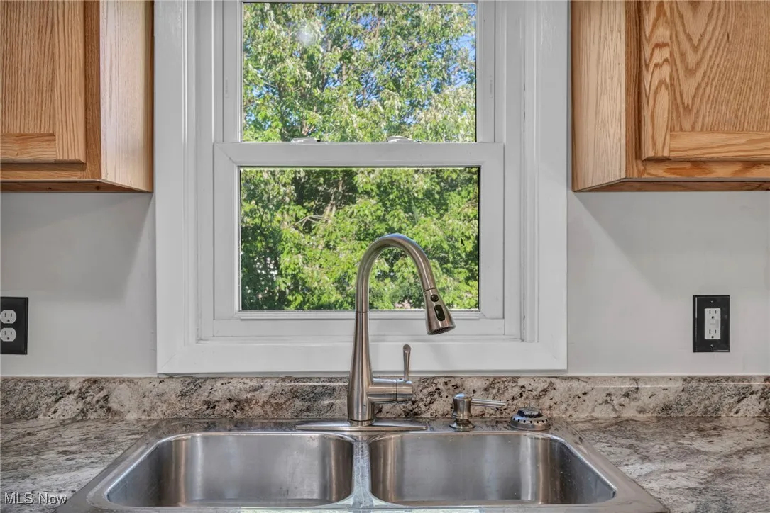 Kitchen view of dark stone counters and brown cabinets