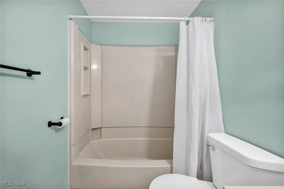 Full bath featuring shower / bath combo with shower curtain and toilet