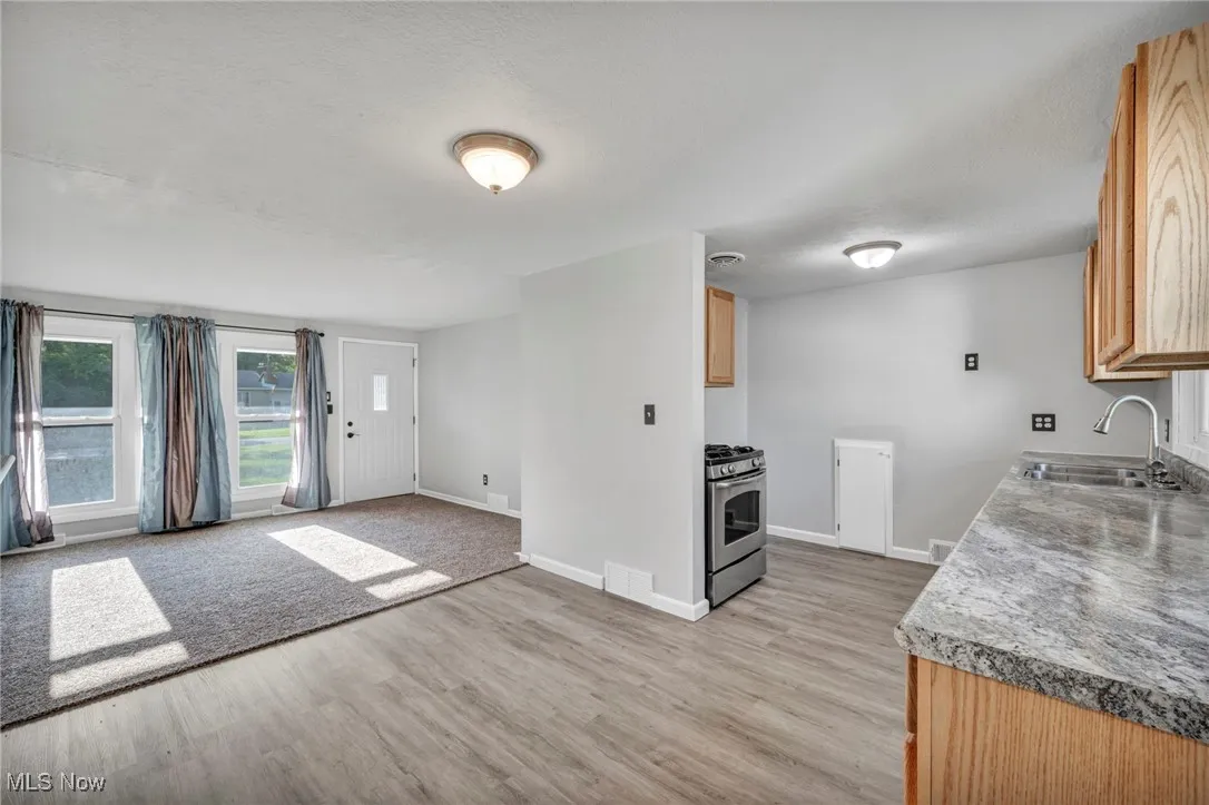 Kitchen featuring gas range, light wood-style floors, light countertops, and light brown cabinets